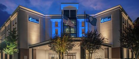 Ein Hotel mit moderner Fassade, einer amerikanischen Flagge und einem Schild mit der Aufschrift 'Hotel Indigo'.