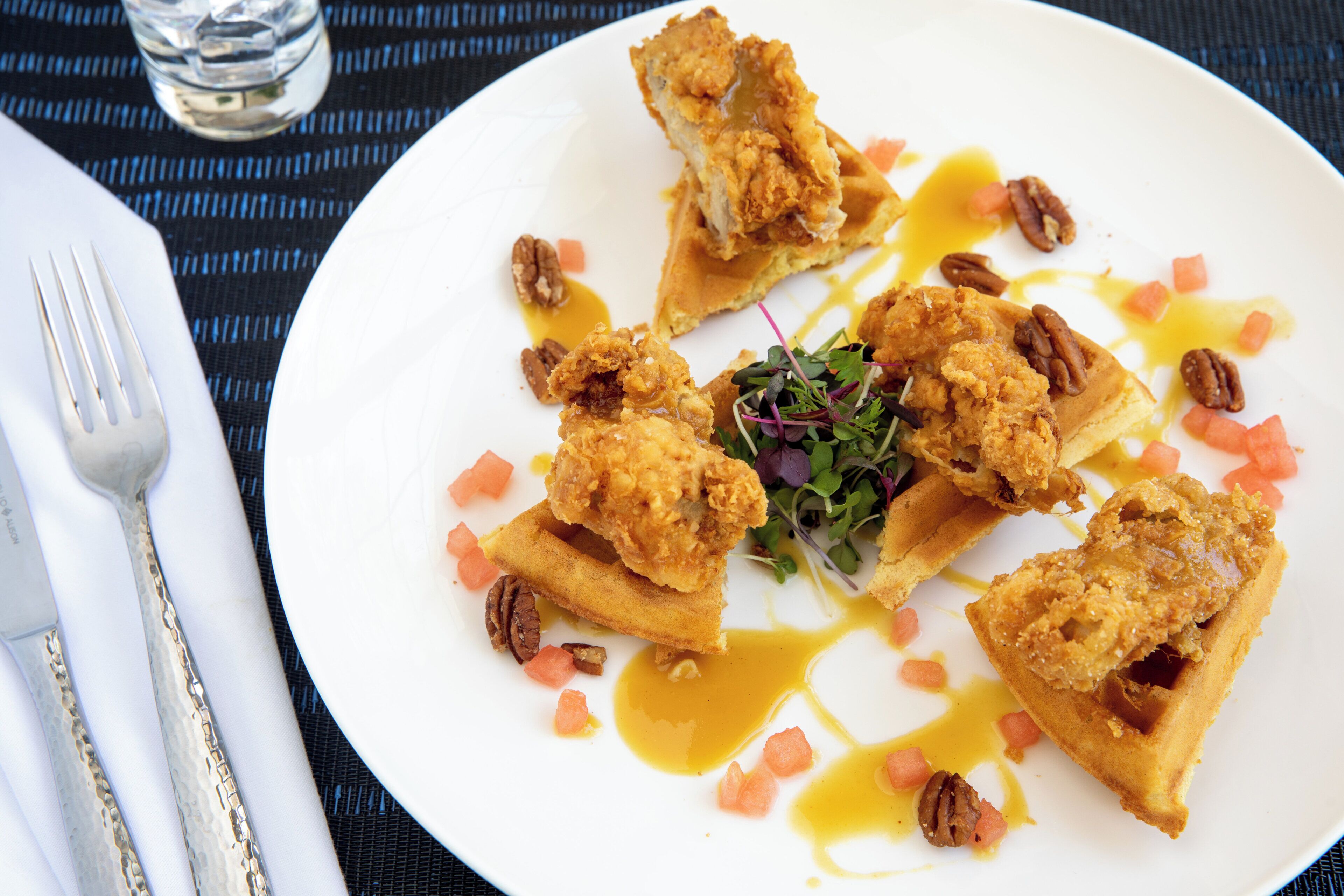 Un piatto con pollo fritto, waffle e un'insalata.