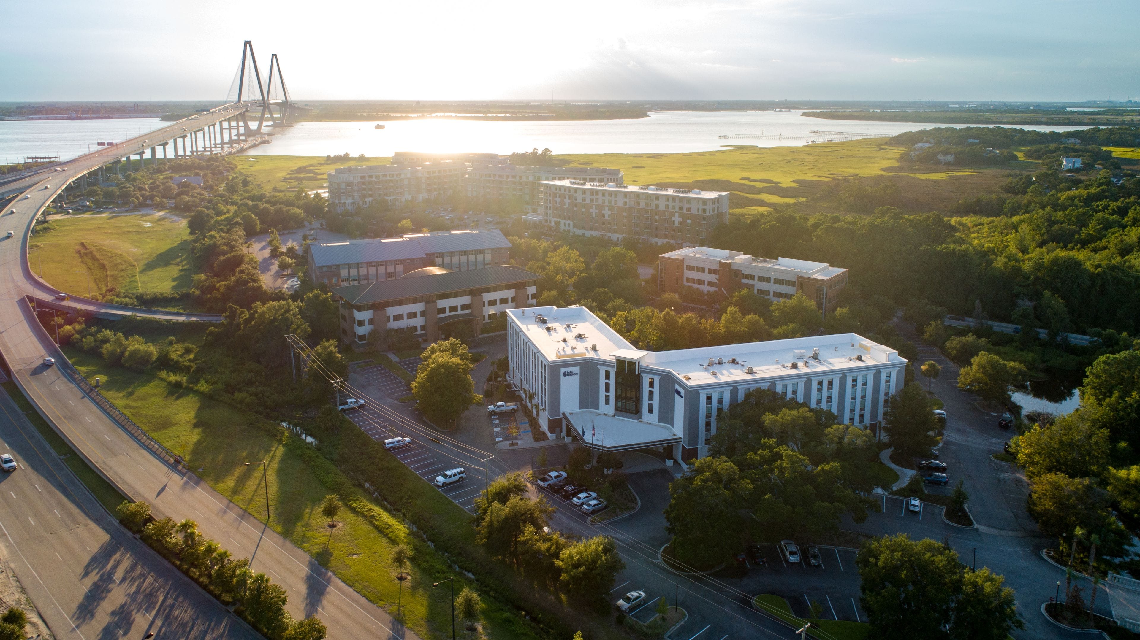 An aerial view of a campus with multiple buildings, roads, and a bridge.