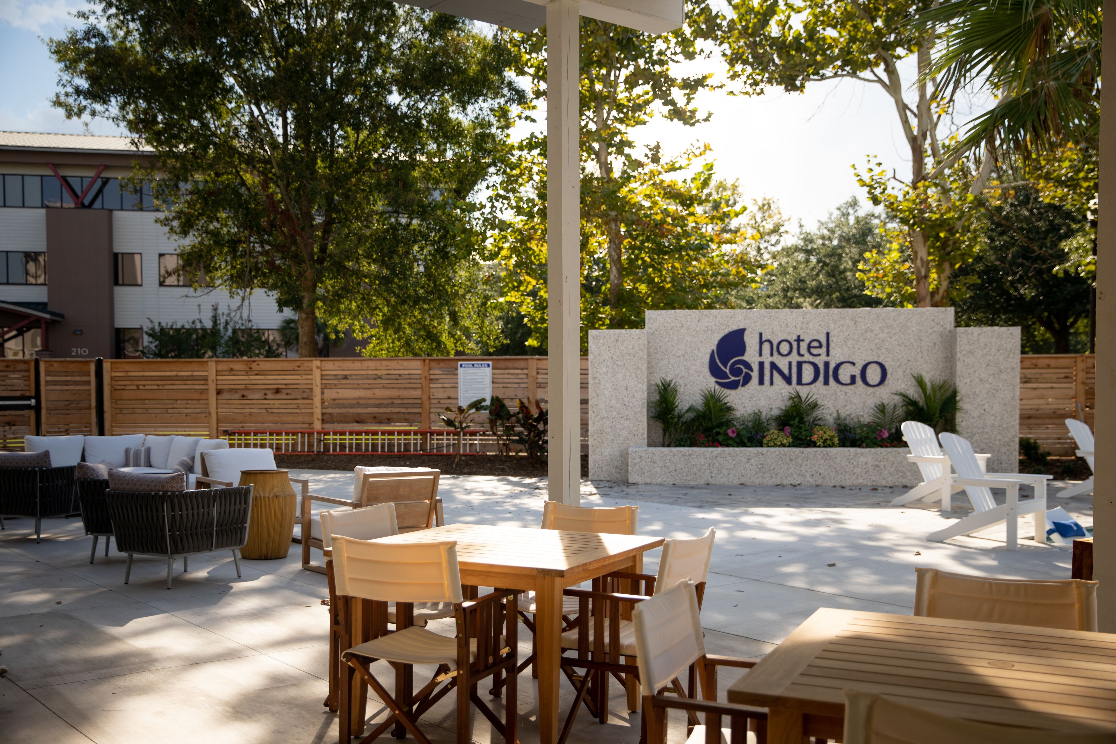 Un espace extérieur aménagé avec des tables et des chaises, une enseigne indiquant « Hôtel Indigo », et un bâtiment en arrière-plan.