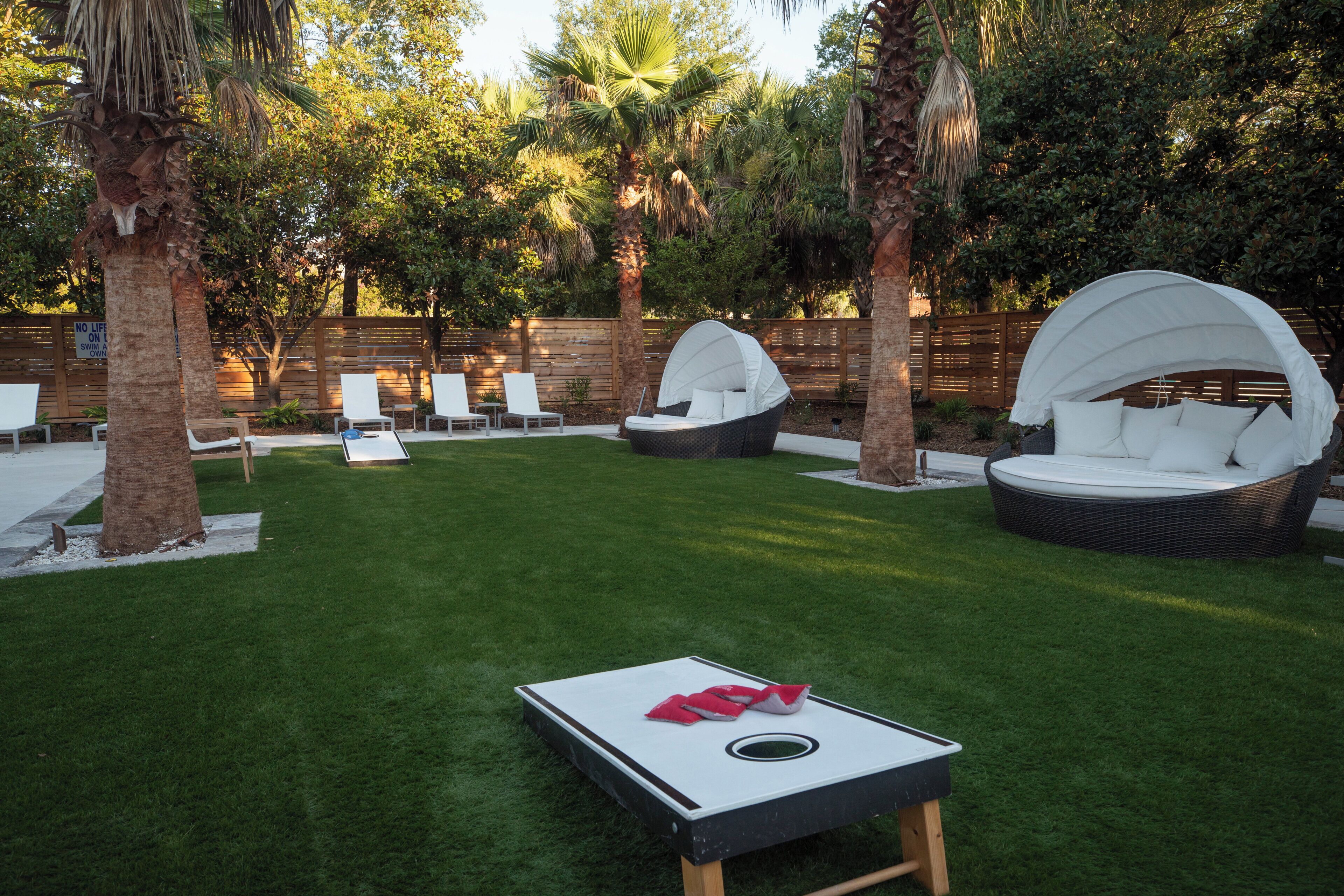 A backyard with a lawn, white lounge chairs, and a ping pong table.