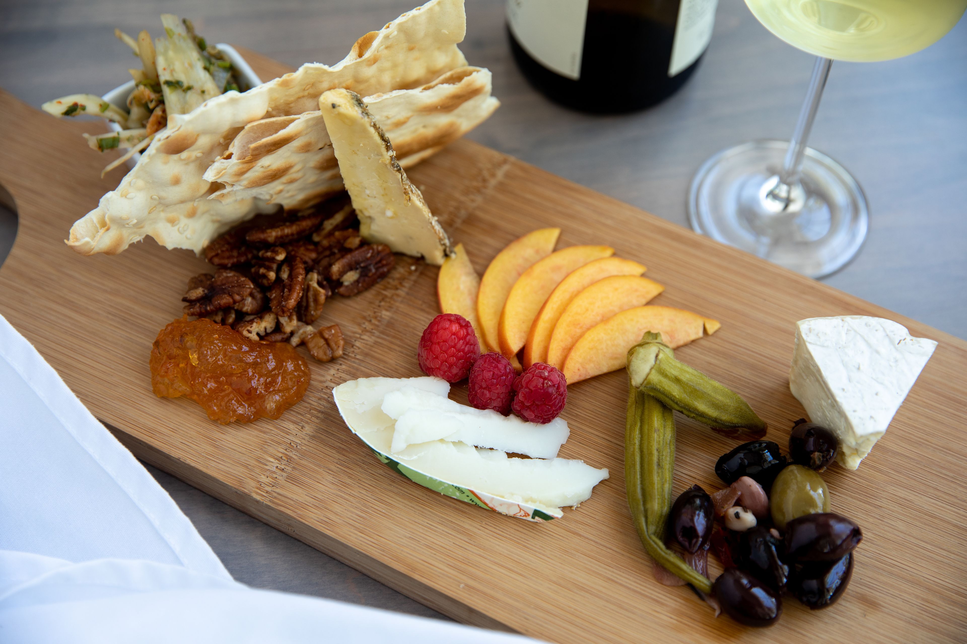 Una tabla de madera con varios quesos, frutas y frutos secos.
