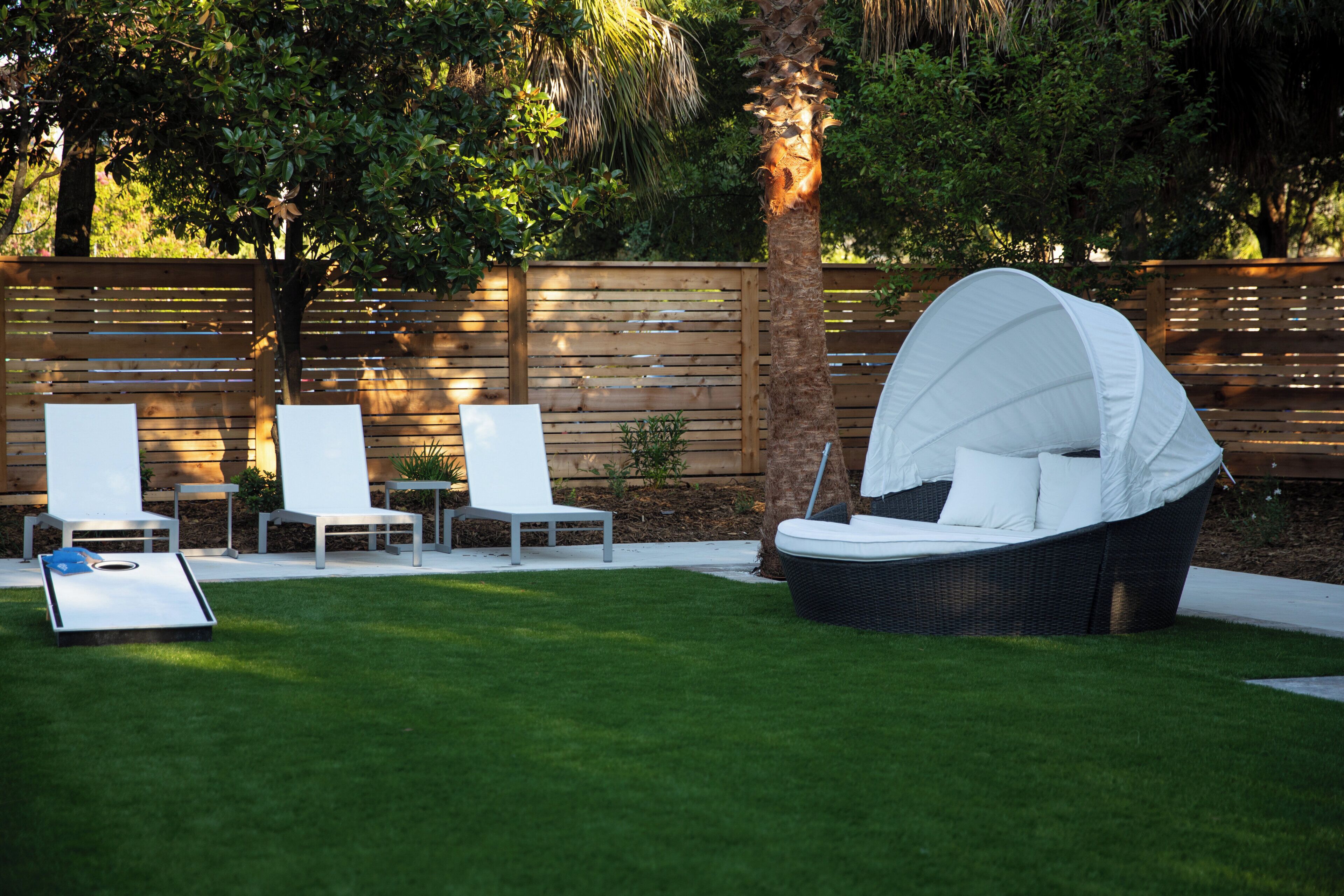 Un patio con zona de estar techada, tres sillones de descanso y una mesita.