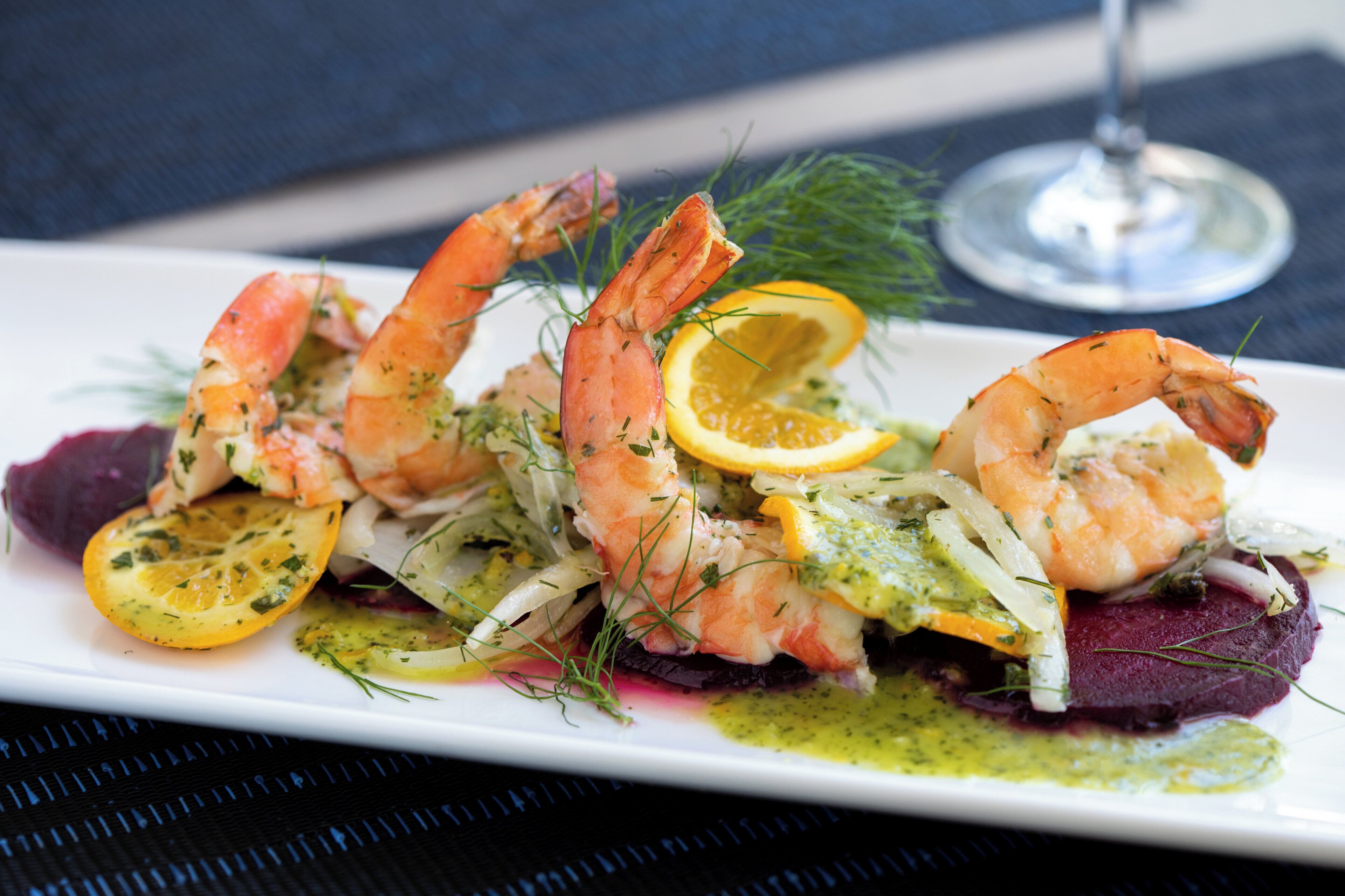 A plate of food with shrimp, lemon slices, and greens.