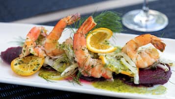 A plate of food with shrimp, lemon slices, and greens.