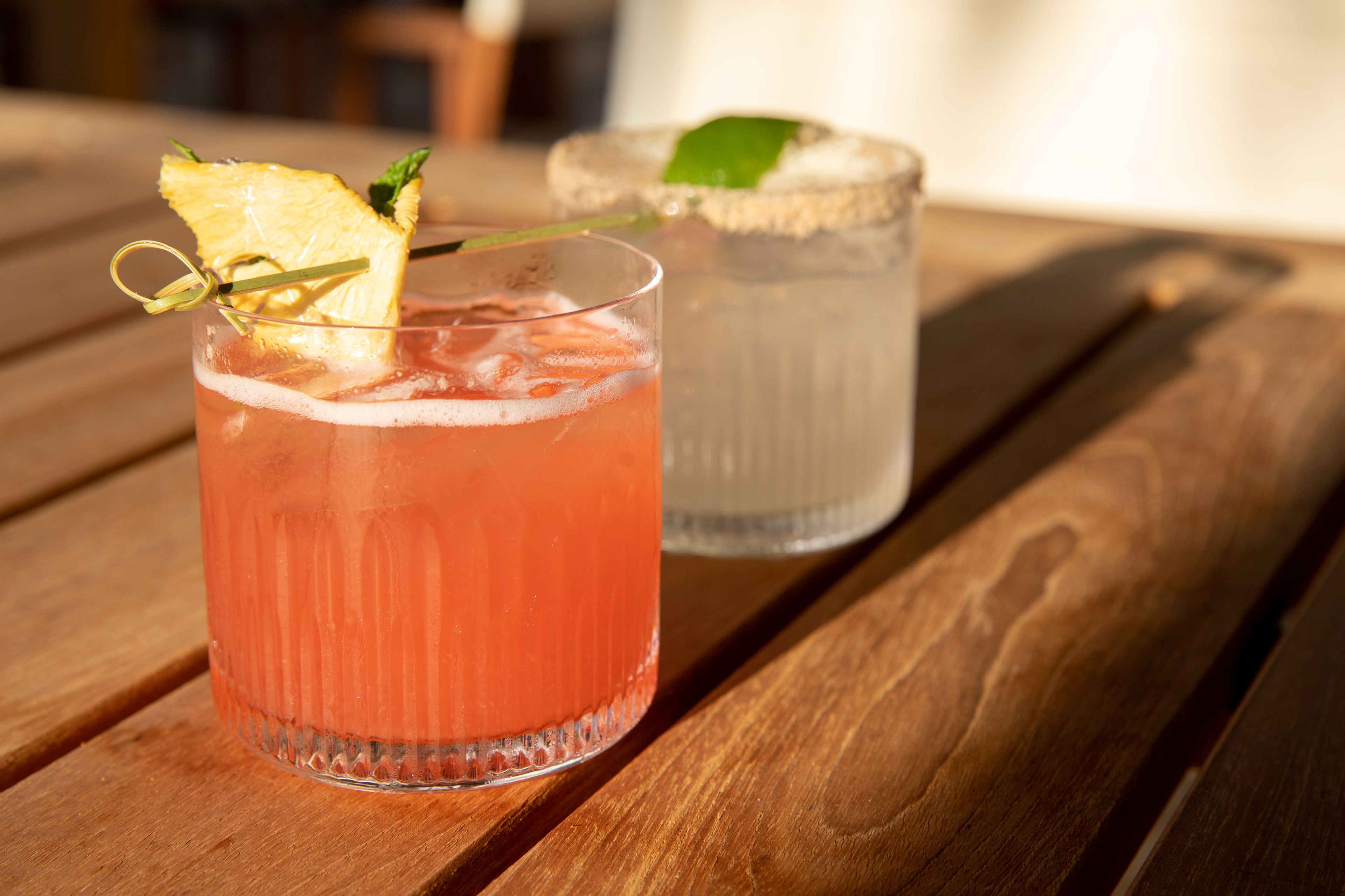 Two glasses of beverages on a wooden table.