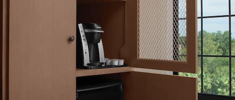 A coffee maker on a shelf, a trash bin, and a window with a view of trees.