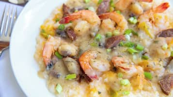 Una porzione di zuppa di pesce con gamberi, patate e cipollotti.