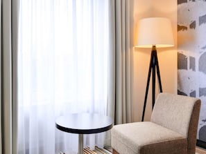 A hotel room with a round table, a chair, a floor lamp, and sheer curtains. - Mercure Hotel Hannover Oldenburger Allee (Hannover)
