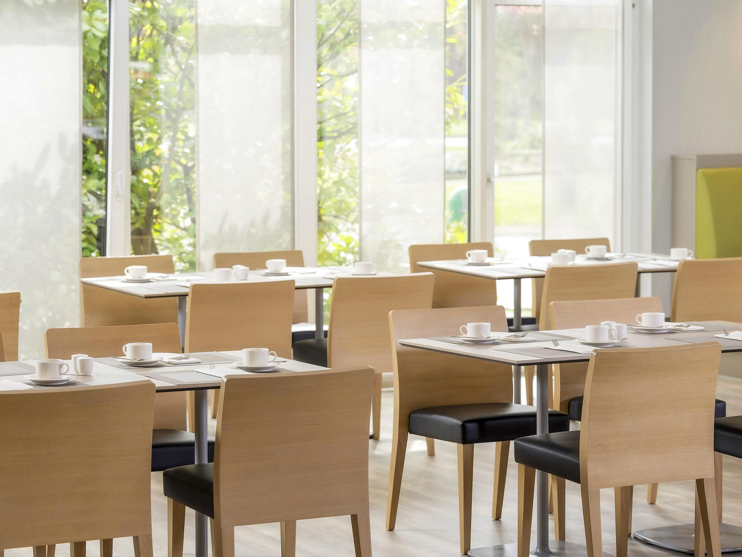 Un comedor moderno con mesas y sillas dispuestas para los huéspedes.