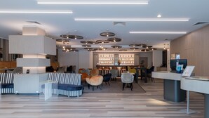A modern lobby with a bar area, seating arrangements, and a reception desk.