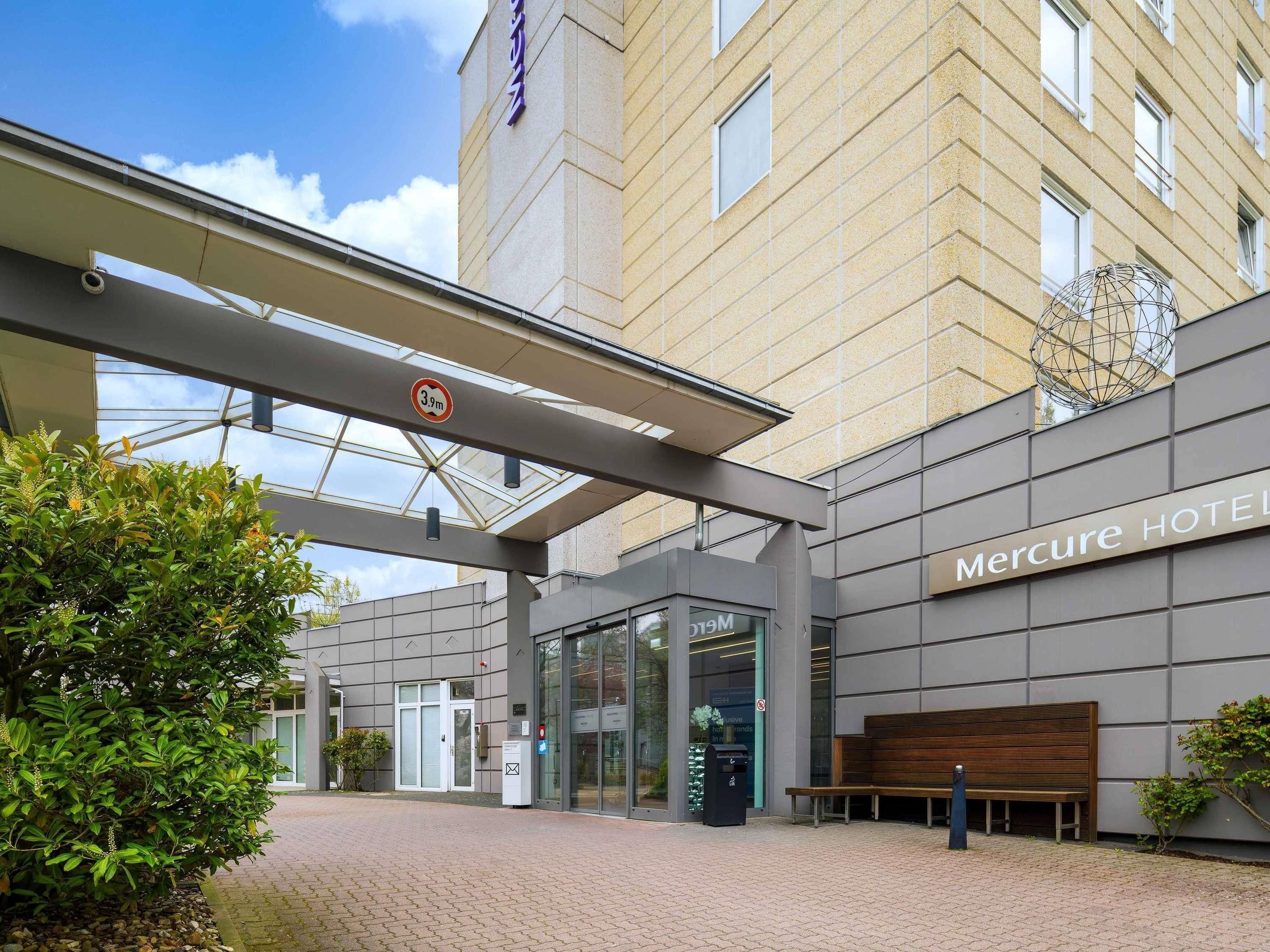 L’entrée d’un hôtel Mercure, avec un passage couvert, un banc et une porte en verre.