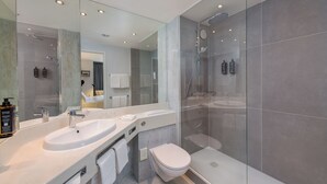 A modern bathroom with a glass-enclosed shower, a double sink vanity, and a toilet.