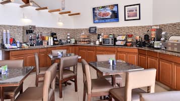 A restaurant with a kitchen counter, seating area, and various appliances.