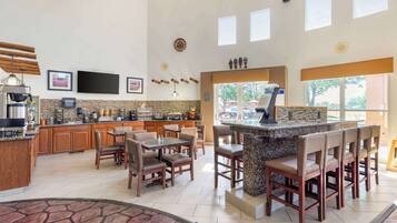 Eine geräumige Küche mit Barbereich, Holzschränken und einer Steinrückwand.