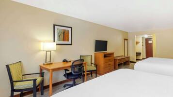 Una habitación de hotel con dos camas, un escritorio con silla, una televisión y un aparador.