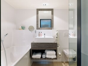 Un baño moderno con bañera, lavamanos, inodoro y tocador con espejo.
