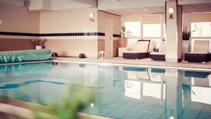 An indoor swimming pool with lounge chairs and a potted plant. - Carlton Beach (The Hague)