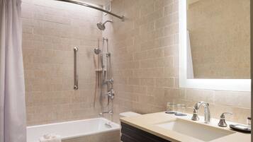 A modern bathroom with a bathtub, shower, and two sinks.