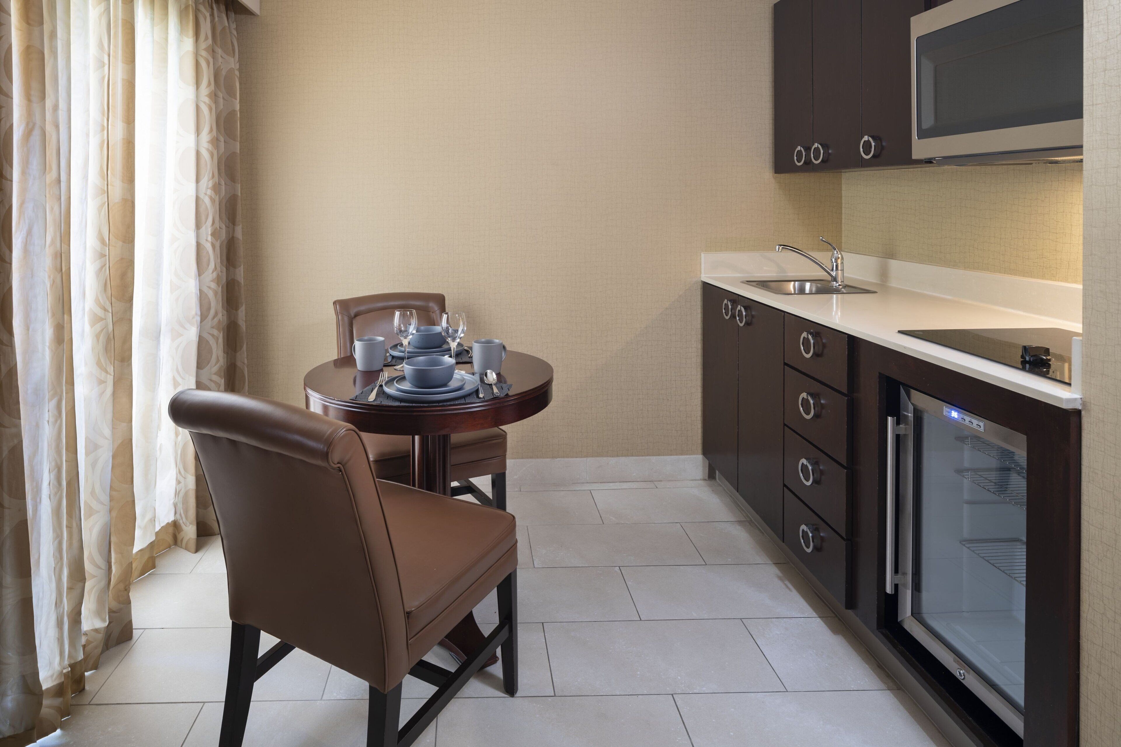 Una cocina compacta con una mesa de comedor, sillas, microondas y pileta.