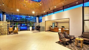 Un lobby amplio con techo de madera, un mostrador de recepción, zona de estar y ventanas grandes.