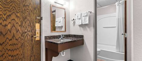 Un baño con puerta de madera, un lavabo con espejo y zona de ducha.