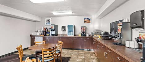 Cuina moderna amb armaris de fusta, taula de dinar amb caires i zona de cafè.