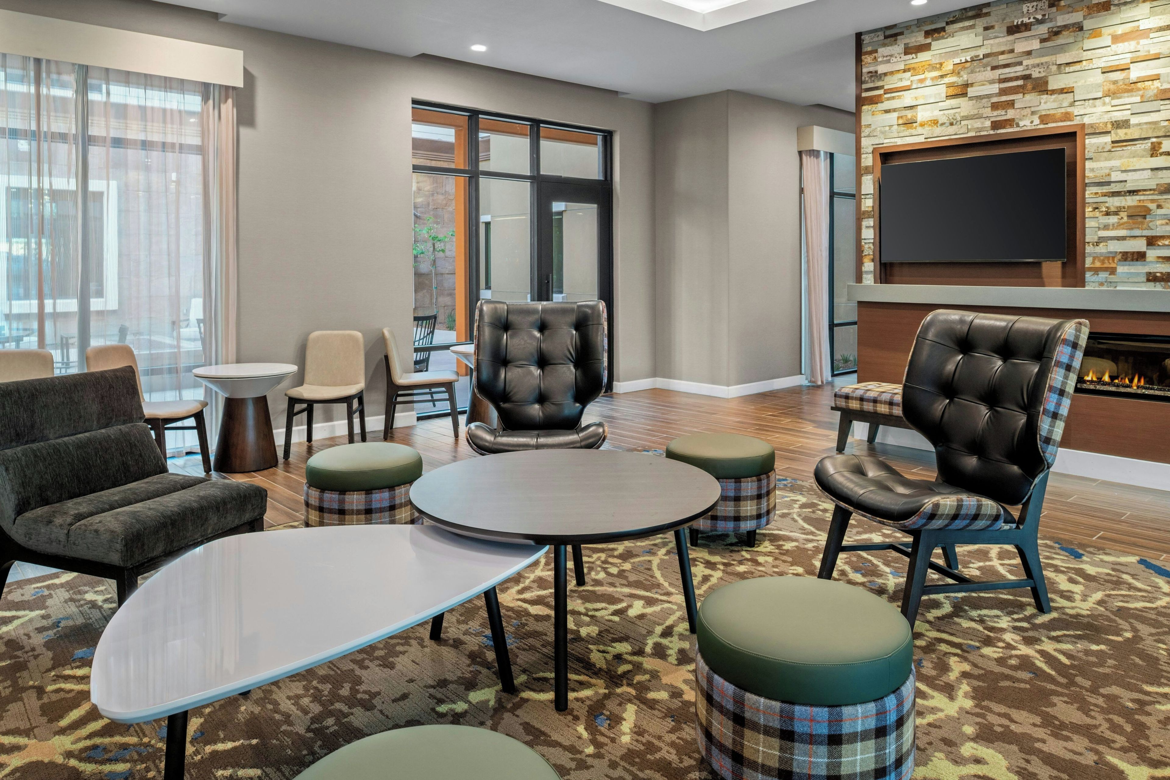 Un salón de hotel con sillones de cuero, un televisor de pantalla plana y una chimenea.