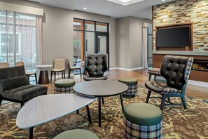 Eine Hotel-Lounge mit Ledersesseln, einem Flachbildfernseher und einem Kamin.