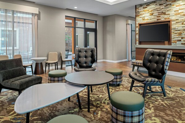 Un salon d’hôtel avec des fauteuils en cuir, un téléviseur à écran plat et une cheminée.