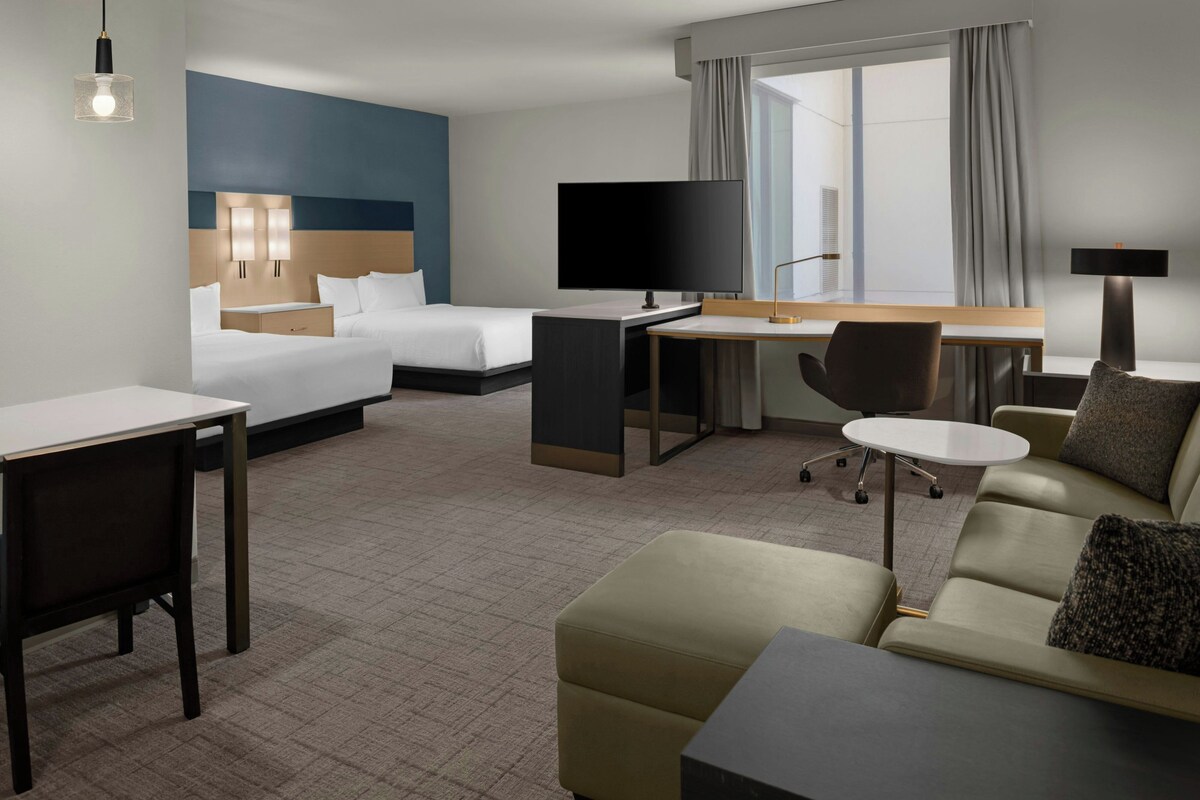 A hotel room with a bed, a desk, a TV, a sofa, and a chair.