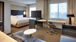 Una camera d'albergo moderna con un letto, una scrivania, una sedia e un'ampia finestra vista.