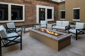 An outdoor seating area with a fire feature, stone walls, and modern furniture. - Residence Inn by Marriott Claremont (Claremont)