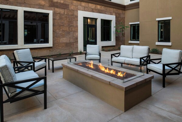 An outdoor seating area with a fire feature, stone walls, and modern furniture. - Residence Inn by Marriott Claremont (Claremont)