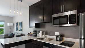Una cucina moderna con mobili scuri, elettrodomestici in acciaio inossidabile, un forno a microonde integrato e una grande isola con lavello.