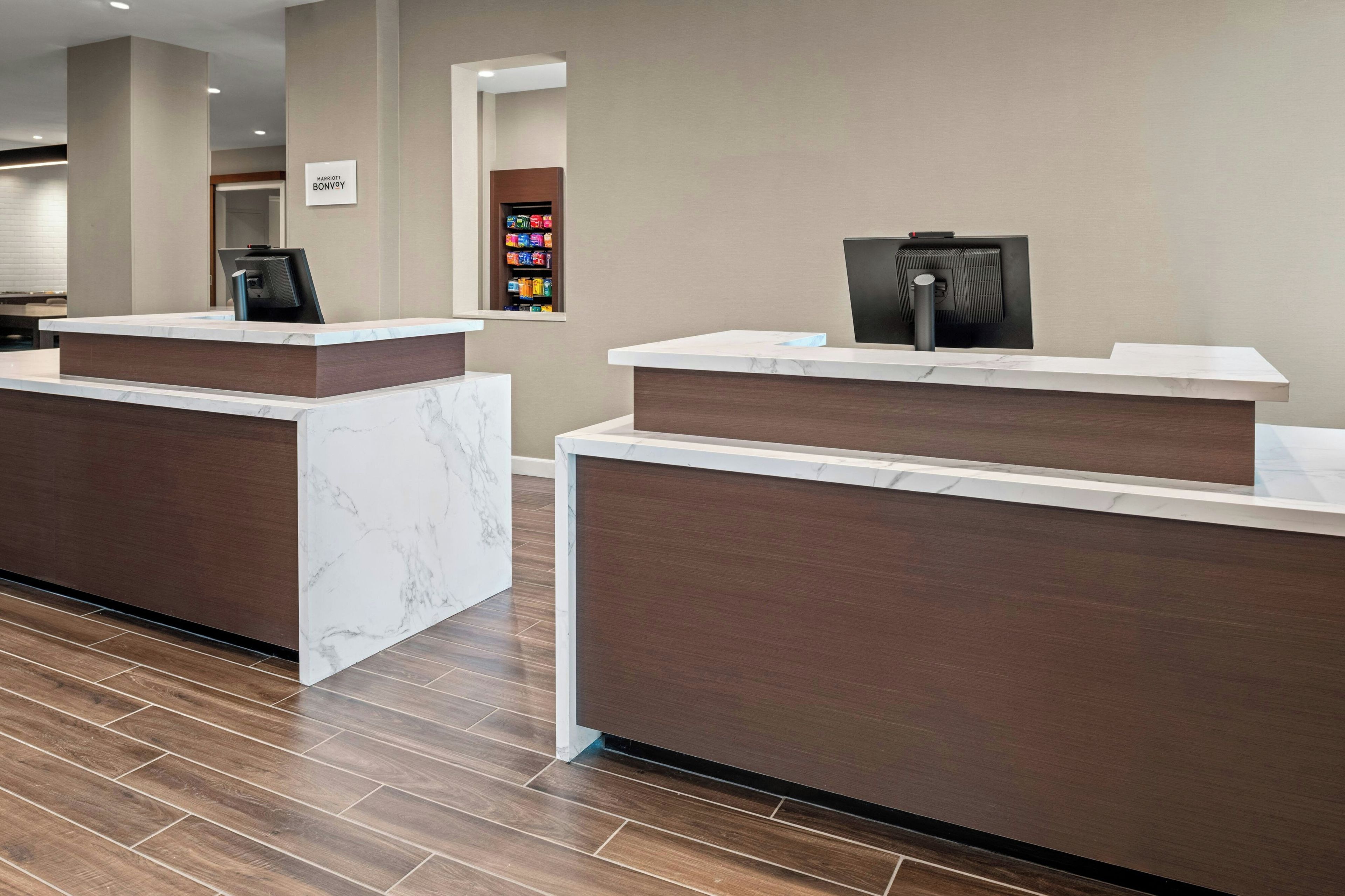 A hotel reception area with marble counters and a digital check-in kiosk.