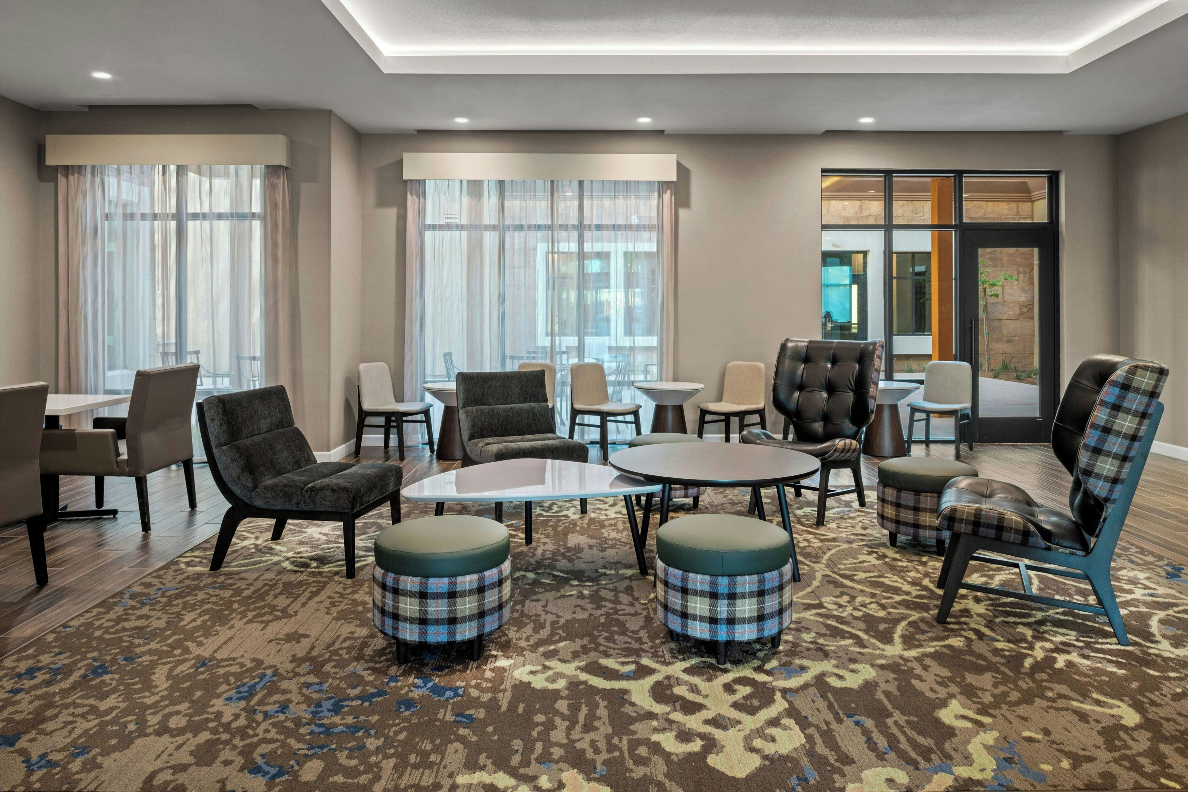 A hotel lobby with multiple seating areas, including sofas and chairs, arranged around a central coffee table.