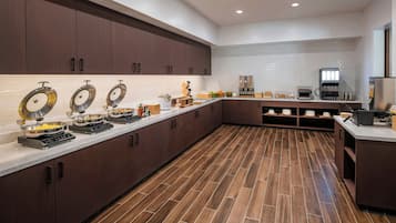 Una cocina moderna con una encimera amplia, equipada con diversos electrodomésticos y alimentos.