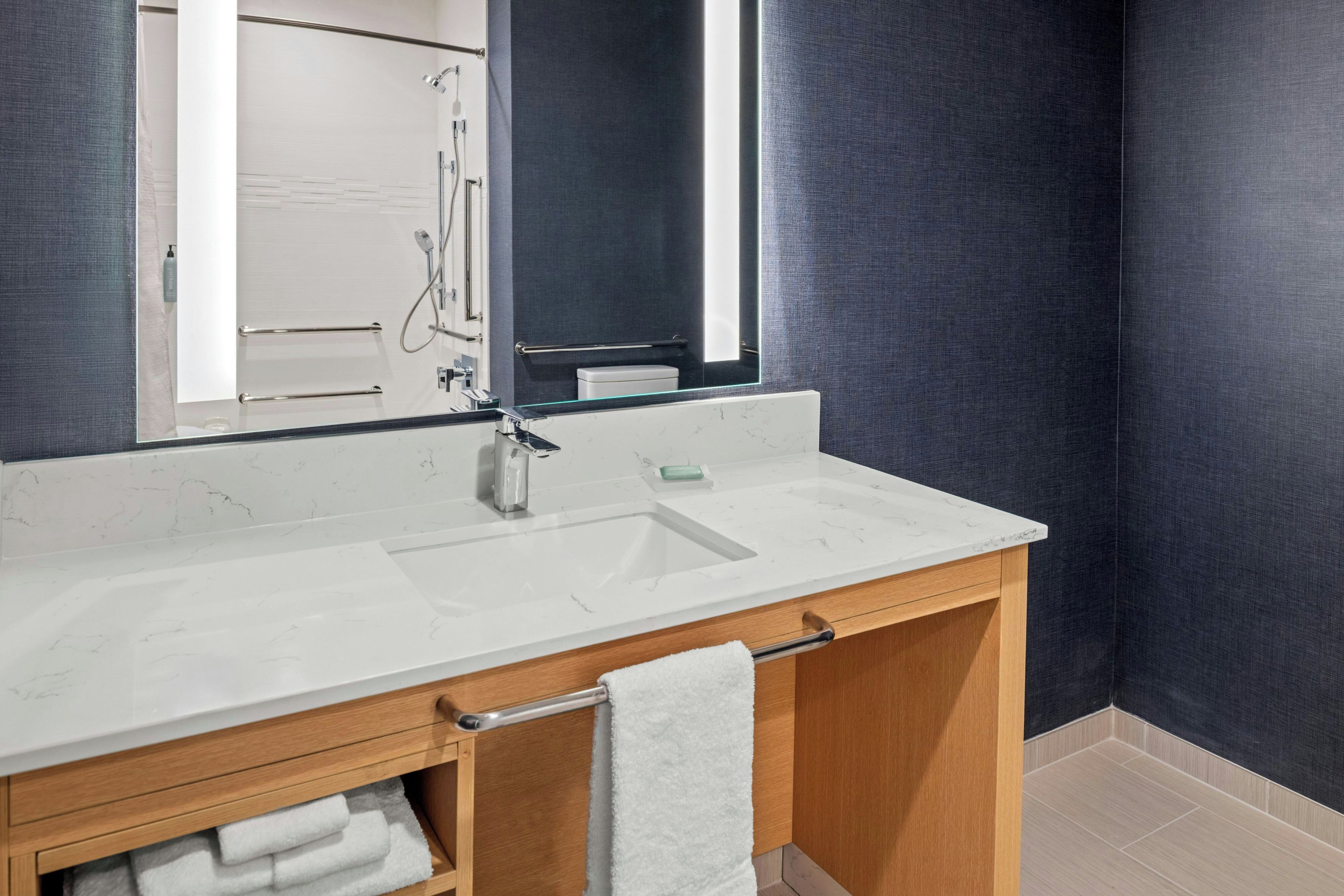 A bathroom with a white marble sink, a mirror, and a towel rack.