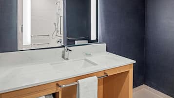 A bathroom with a white marble sink, a mirror, and a towel rack.