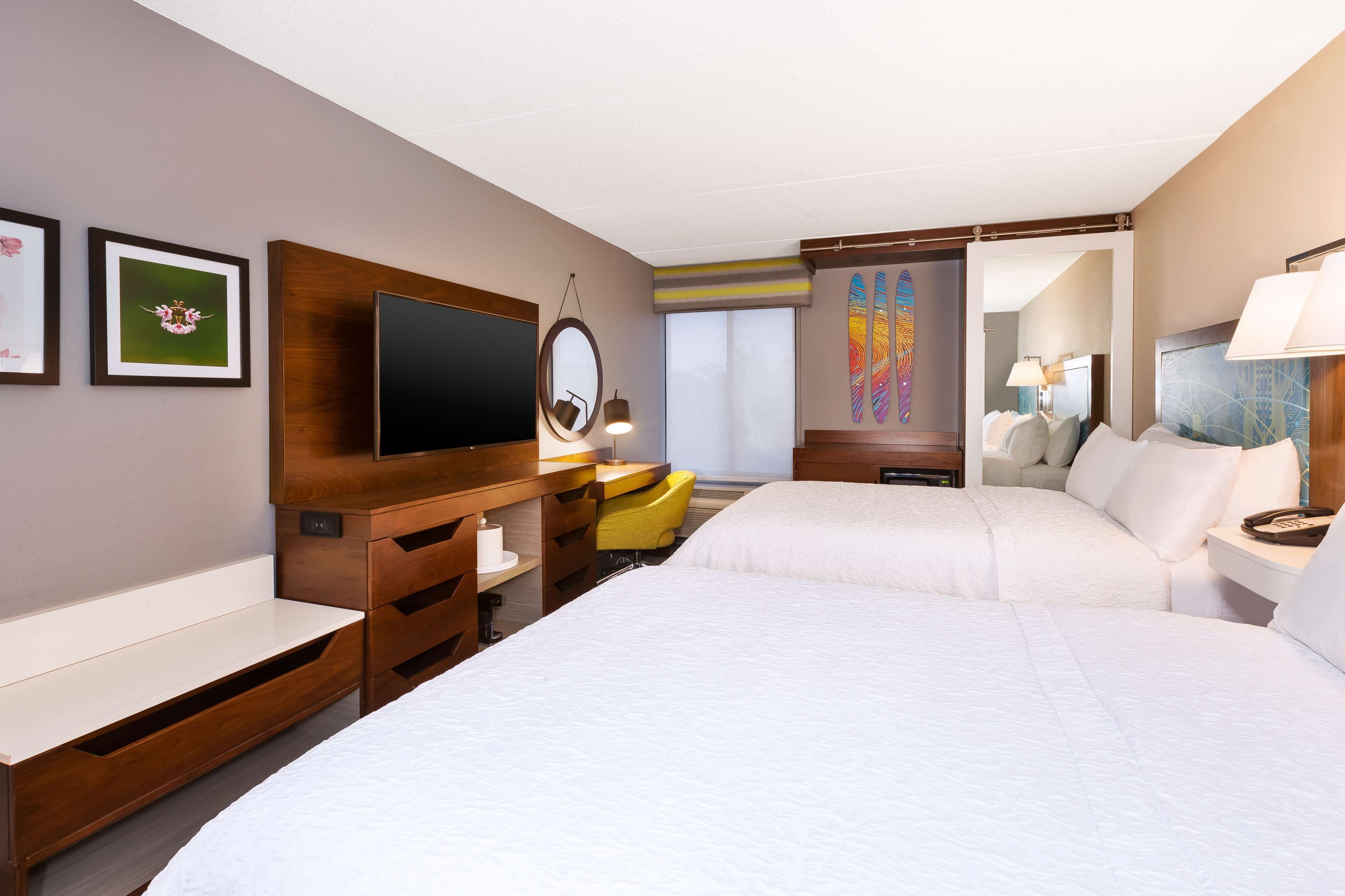 Une chambre d’hôtel avec un grand lit, un bureau doté d’un téléviseur à écran plat, une chaise et une fenêtre donnant sur un paysage agréable.