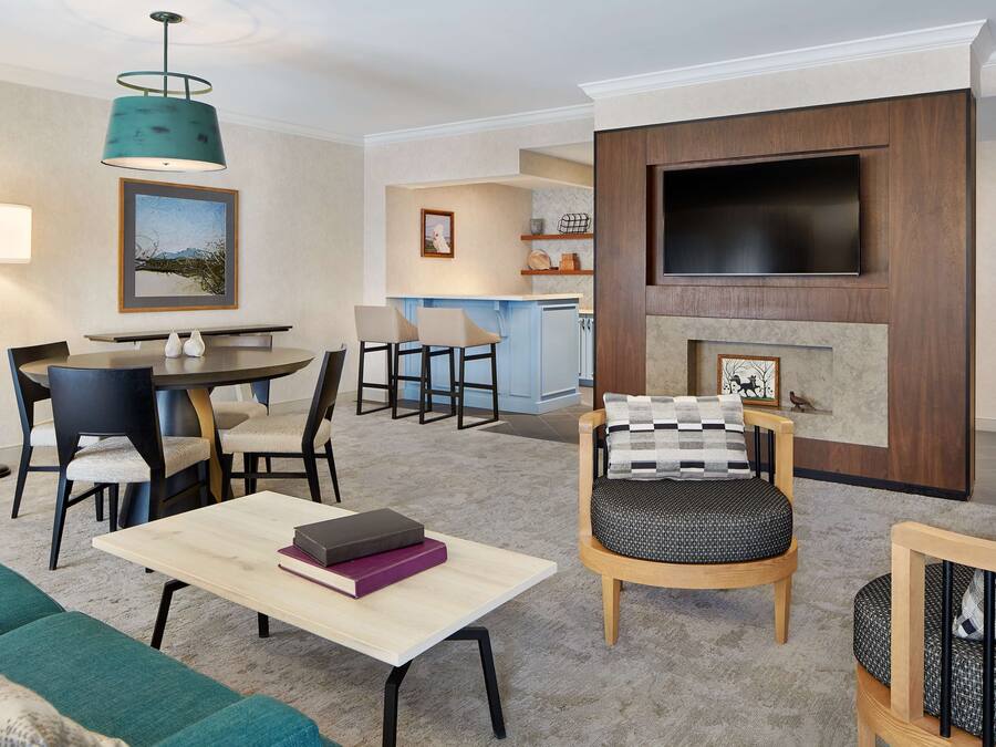 A modern living room with a dining area, a fireplace, and a TV mounted on the wall.