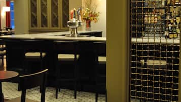 A bar area with wooden flooring, bar stools, pendant lighting, and a view through a wire mesh window.