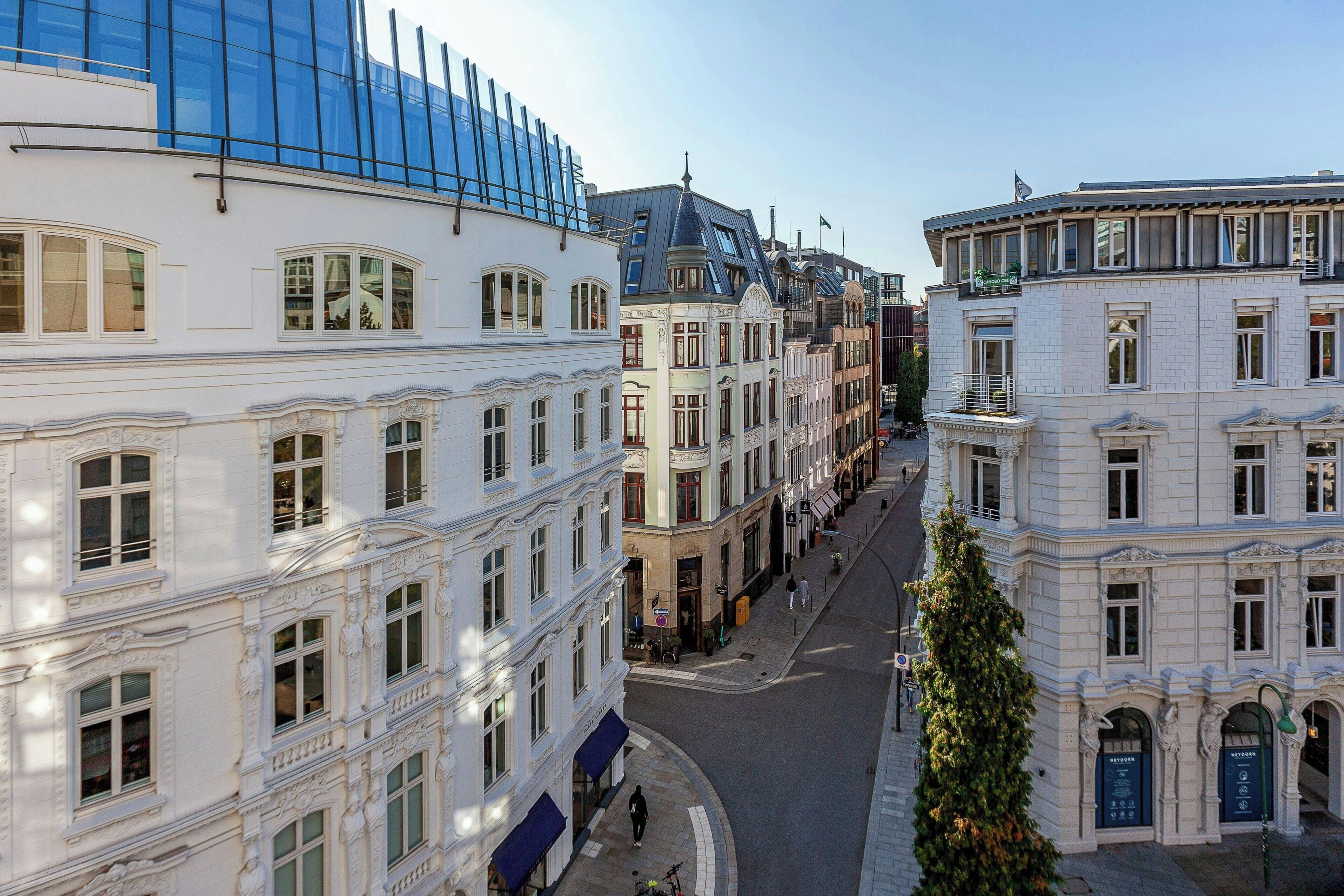 Une vue de rue avec des bâtiments à l’architecture classique, notamment des façades richement décorées et de grandes fenêtres.