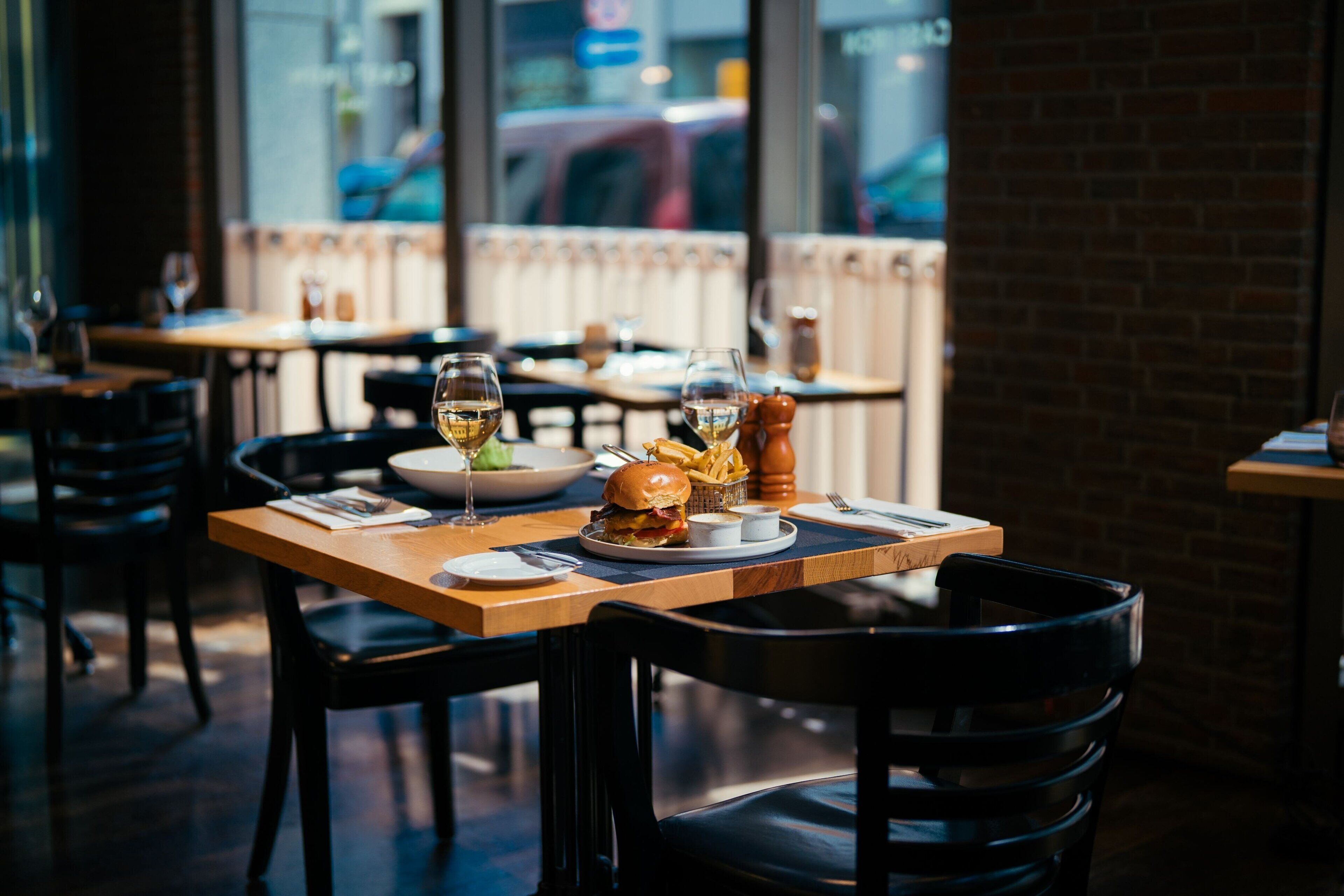 A restaurant interior with tables set for dining, chairs, and a window view.