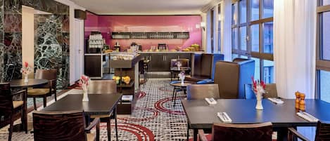 Un comedor de hotel con barra central, distribuciones de asientos y alfombra estampada.