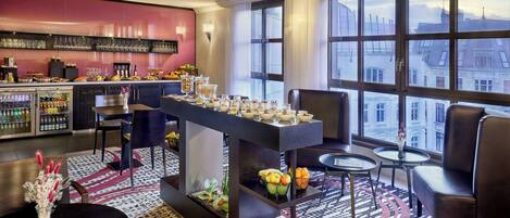 A modern hotel lobby with a bar area, seating, and a large window offering a city view.