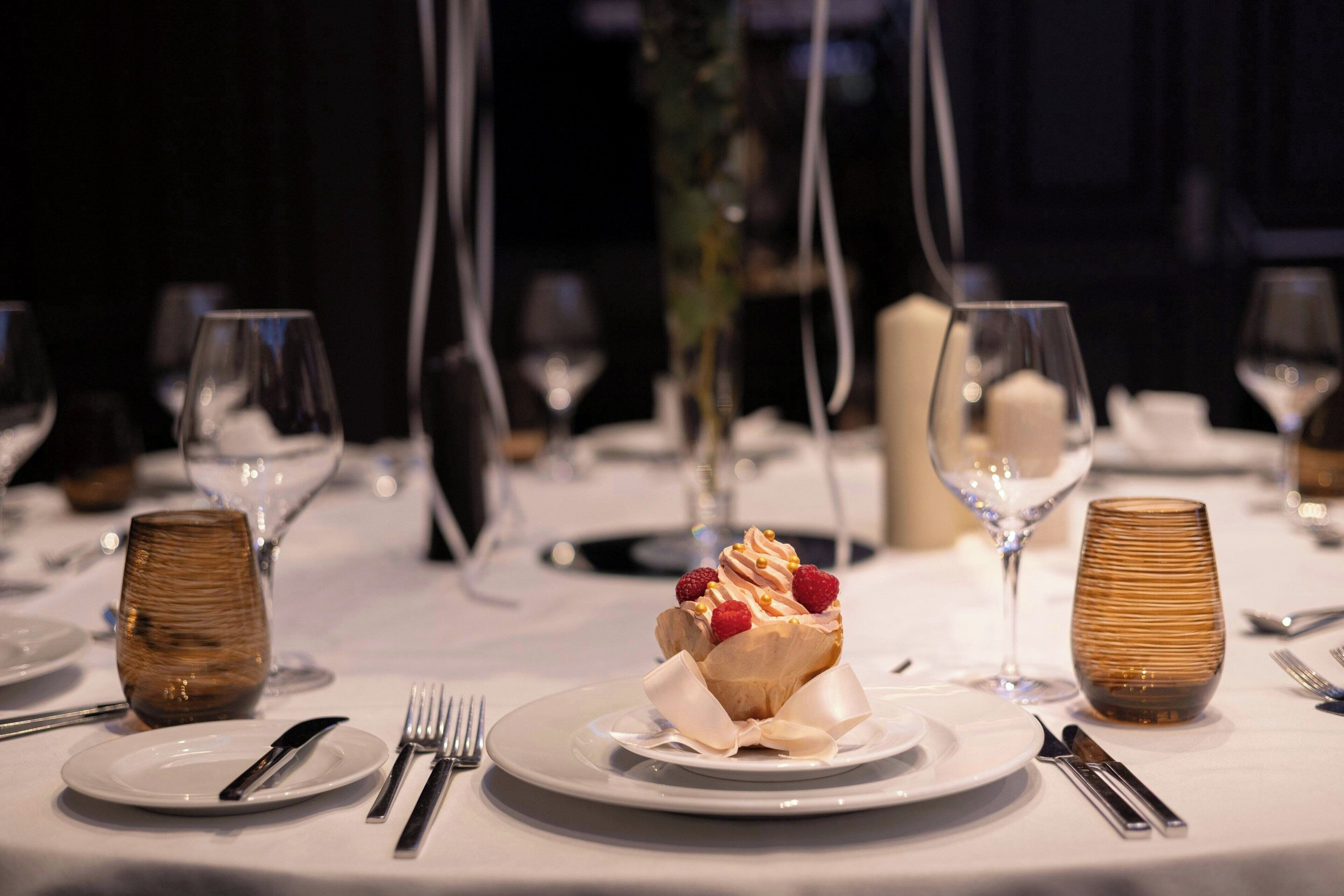 A dining table set with plates, cutlery, and a dessert centerpiece.