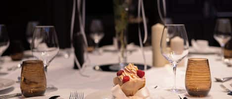 A dining table set with plates, cutlery, and a dessert centerpiece.