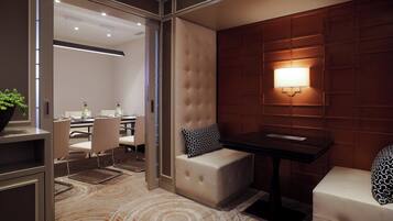 A modern hotel room with a seating area, a table, and a wall-mounted lamp.